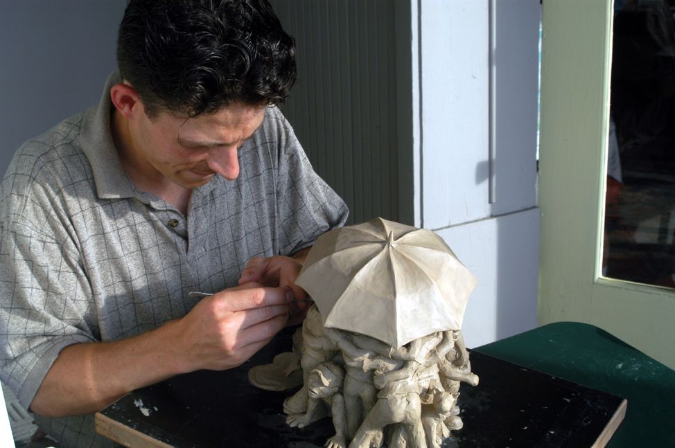 Jeff John sculpting a clay figure in the studio